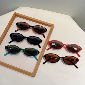 Retro oval Y2K sunglasses collection in various colors displayed on a wooden tray