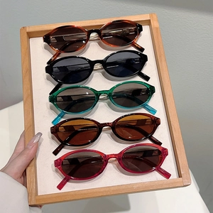 Detail showing five colors of oval Y2K retro sunglasses on a wooden tray