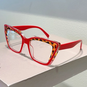 Retro red cat-eye glasses with leopard print inner frame on a white display stand
