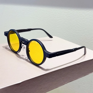 Detail view of retro round sunglasses featuring yellow lenses and black double-bridge frame