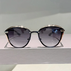 Detailed view of cat-eye sunglasses with golden metal trim on a minimalist display stand