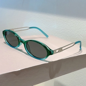 Detail view of oval teal sunglasses with silver hollowed metal temples and grey lenses