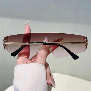 Gros plan de lunettes Y2K sans monture avec verres dégradés marron et détails en métal doré