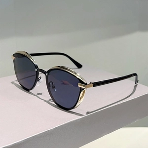 Fashionable black cat eye sunglasses with gold accents on a grey geometric stand