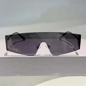 Détail de lunettes de soleil Y2K sans monture noires sur un socle gris minimaliste