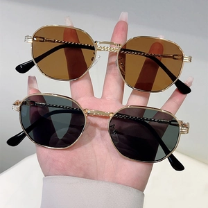 Detail of twisted metal frame sunglasses with hexagonal lenses in brown and dark grey