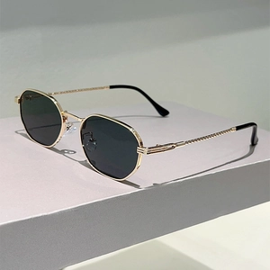 Detail of gold hexagonal sunglasses frame with twisted metal texture and black lenses