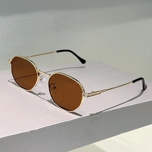 Detail of gold metal sunglasses frame featuring twisted spiral temples and brown lenses