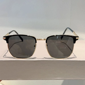 Detail of retro semi-rimless sunglasses featuring black upper frame and gold metal accents
