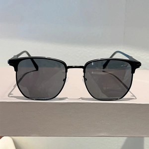 Front view of semi-rimless sunglasses with dark lenses on a minimalist stone base