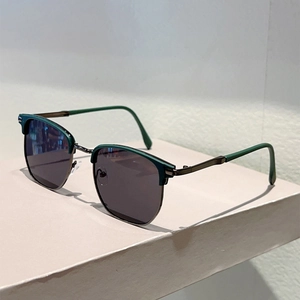 Detail of dark green clubmaster sunglasses with metal half-rim on a white pedestal