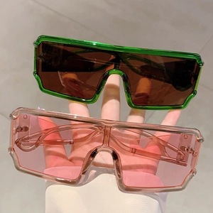 Lunettes de soleil oversize futuristes avec montures transparentes vertes et roses en main
