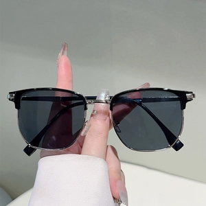 Classic black half-frame sunglasses with retro metal rim and gray lenses in a hand-held view