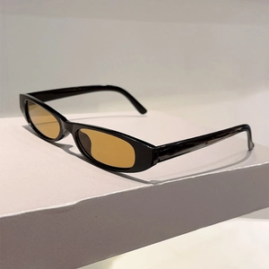 Détail de lunettes de soleil ovales noires avec verres ambrés sur un support minimaliste