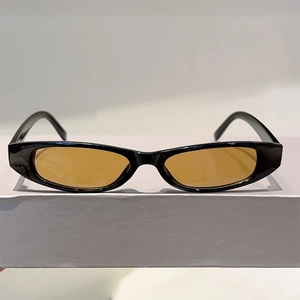 Détail des lunettes de soleil ovales rétro avec monture noire et verres ambre sur un support