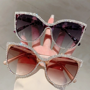 Close-up of cat-eye sunglasses featuring rhinestone-encrusted frames and gradient lenses