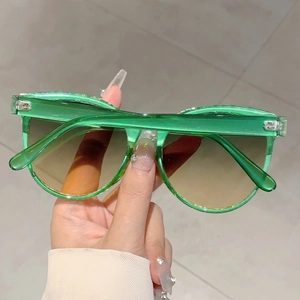 Detail of transparent green oversized cat eye sunglasses with gradient lenses