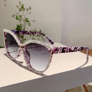 Macro detail of cat-eye sunglasses with purple marble texture and crystal embellishments