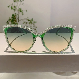 Detail of emerald green cat-eye sunglasses with rhinestone edges and gradient lenses