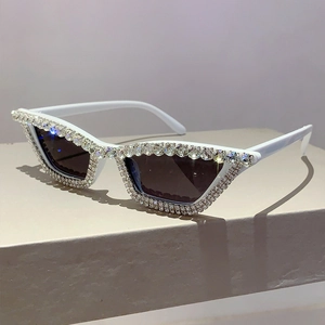 Détail de lunettes de soleil œil-de-chat blanches avec strass de luxe sur socle