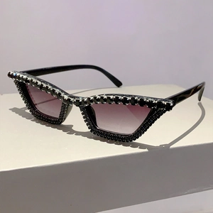 Détail de lunettes œil-de-chat noires à verres dégradés violets avec des strass