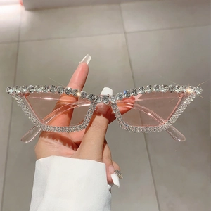 Lunettes de soleil œil de chat roses avec monture ornée de strass tenues à la main de près