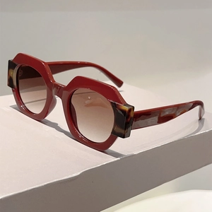 Detail view of bold red geometric sunglasses with brown gradient lenses and tortoise accents