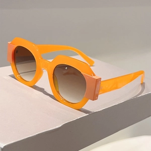 Detail shot of chunky orange hexagonal sunglasses with light brown gradient lenses