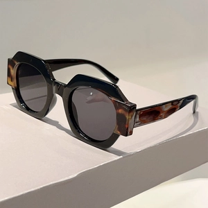Detail of chunky black hexagonal sunglasses featuring tortoiseshell texture on the temples