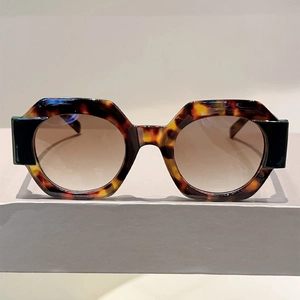 Detail of tortoiseshell hexagonal frame sunglasses with brown gradient lenses