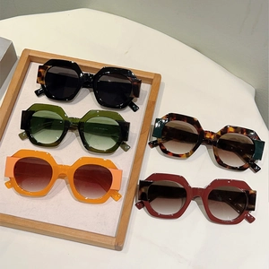 Retro oversized round frame sunglasses in various colors displayed on a wooden tray