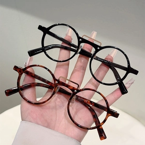 Détail de lunettes rondes rétro noires et écaille avec accents de pont métallique
