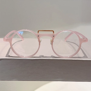 Détail des lunettes rondes en résine rose avec pont en métal doré pour un style rétro