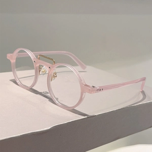 Lunettes rondes rétro rose translucide avec pont en métal doré sur plateau minimaliste