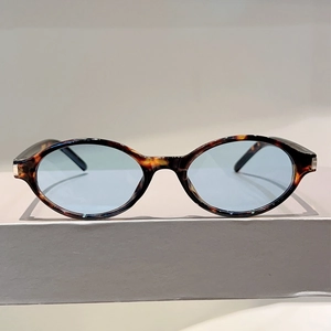 Détail de lunettes de soleil ovales en écaille avec verres bleu clair et charnières