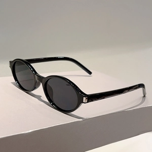 Détail de lunettes de soleil ovales rétro avec monture noire et charnières en métal argenté
