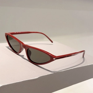 Detail der trendigen dunkelroten Cat-Eye-Sonnenbrille mit grauen Gläsern auf grauem Grund