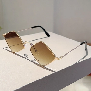 Detailed view of irregular gold metal frames with brown gradient lenses on a minimalist stand