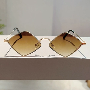 Detail of geometric rhombus sunglasses with thin gold metal frame and brown gradient lenses