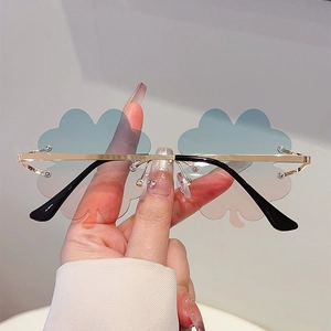 Detalle de gafas de sol sin montura en forma de nube con lentes degradadas azul rosa y marco de oro