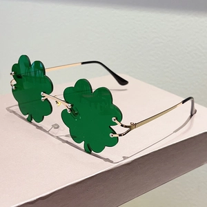 Detalle de gafas de trébol verde con montura de metal dorado y lentes translúcidas de trébol