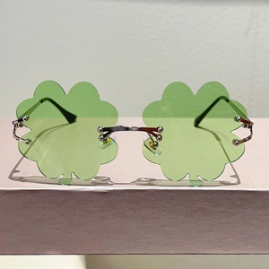 Detalle de lentes verdes en forma de trébol y montura de metal plateado en gafas