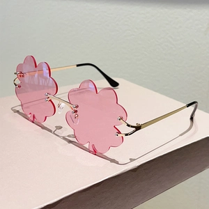 Detalle de lentes sin montura en forma de trébol rosa con patillas de metal dorado