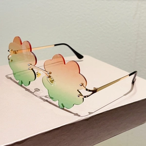 Detalle de lentes de trébol sin montura con degradado naranja a verde y marco dorado
