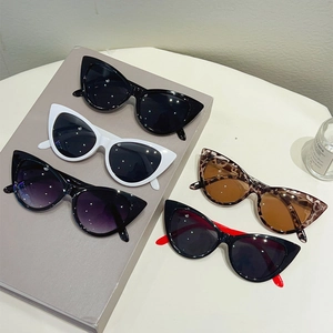 Five assorted retro cat eye sunglasses in various colors displayed on a modern table