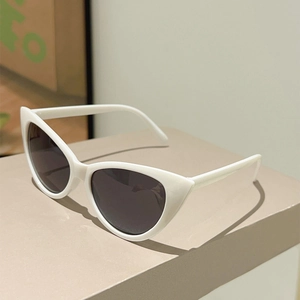 Close-up of vintage cat-eye sunglasses with white frame and dark grey lenses on a stand