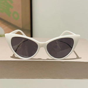 Detail view of retro white cat-eye sunglasses with dark lenses on a geometric display stand