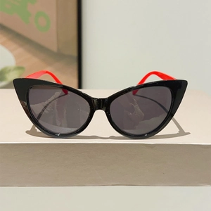 Front view of cat eye sunglasses with black frames and striking red temples on display