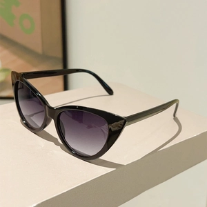Close-up of black cat-eye sunglasses with purple gradient lenses on a display stand