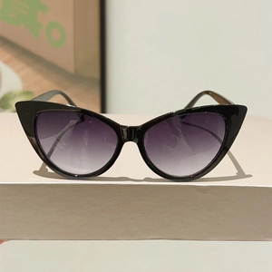 Detailed macro view of black cat-eye sunglasses with purple gradient resin lenses on a tray